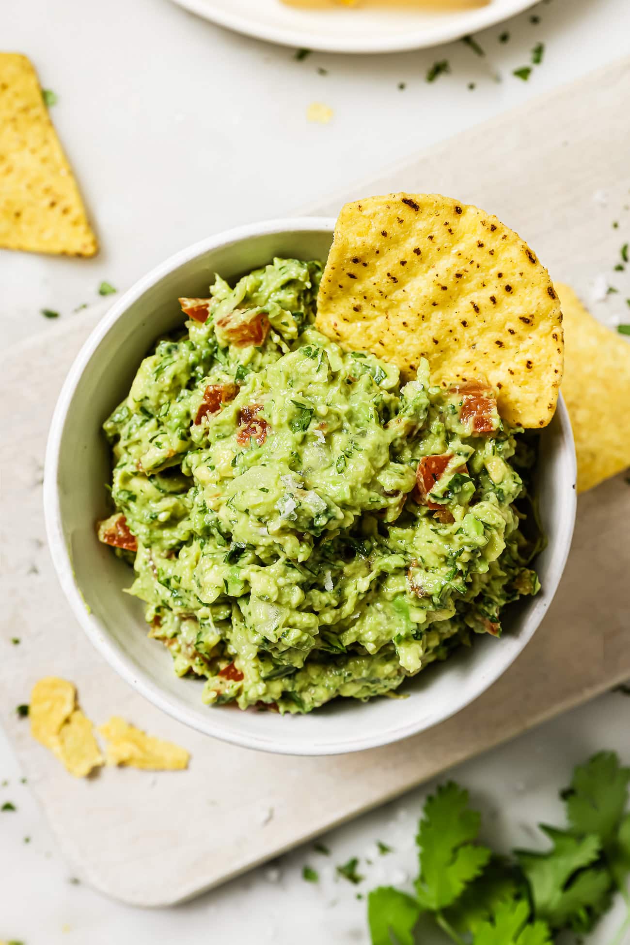 A bowl of easy guacamole with a tortilla chip in it.