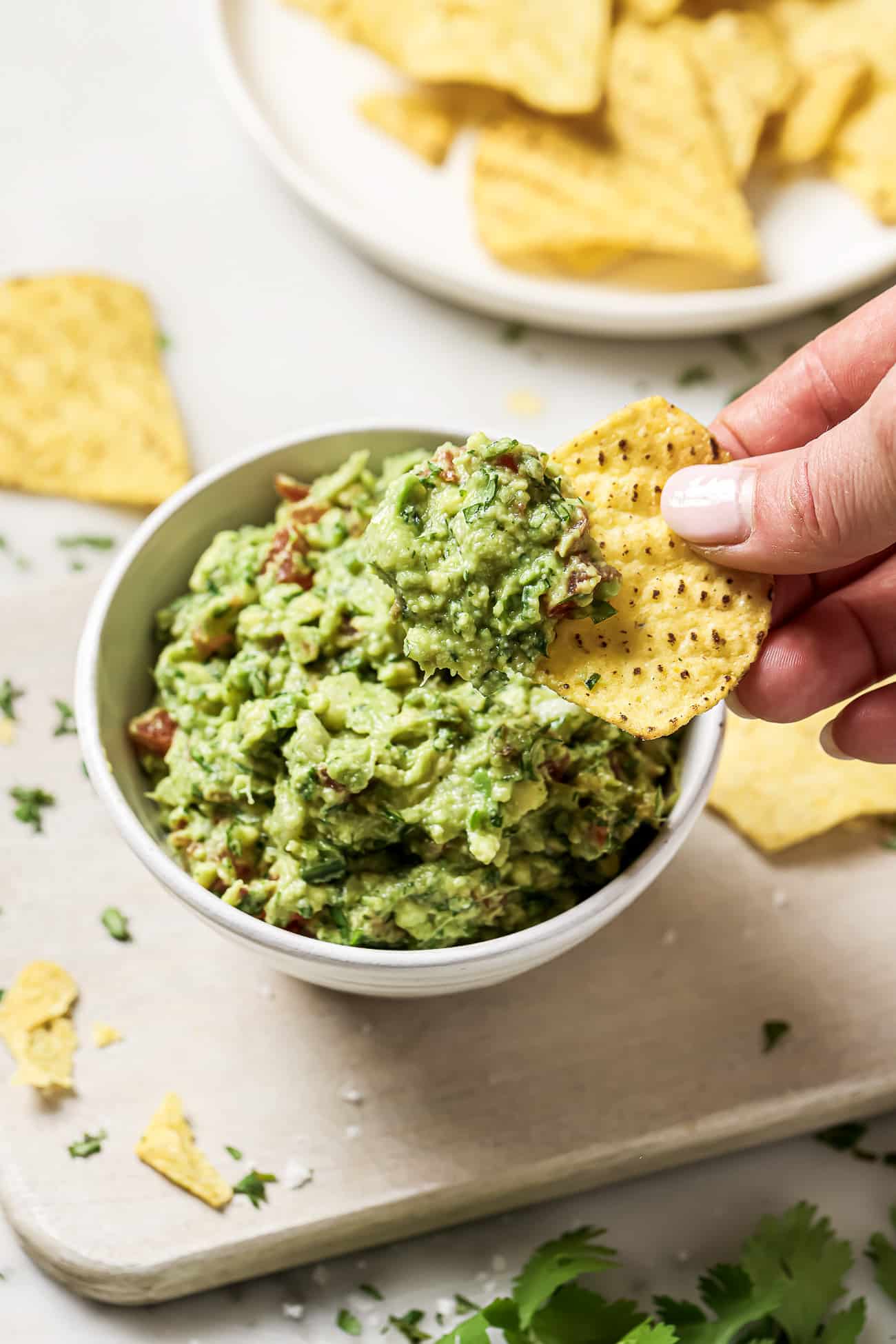 A bowl of guacamole with a tortilla chip.