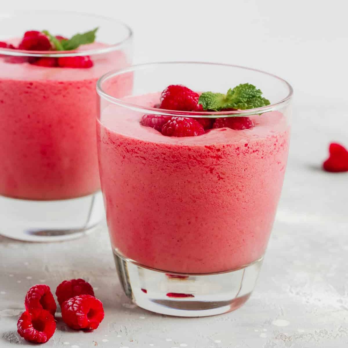 Raspberry smoothie in a glass garnished with fresh berries.