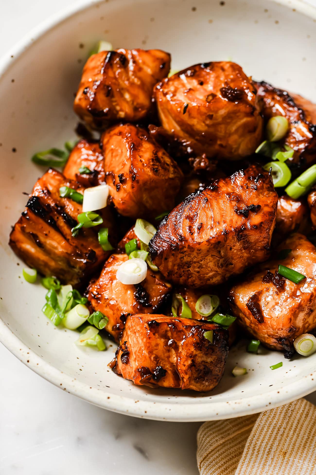 Salmon bites in a bowl garnished with green onions.
