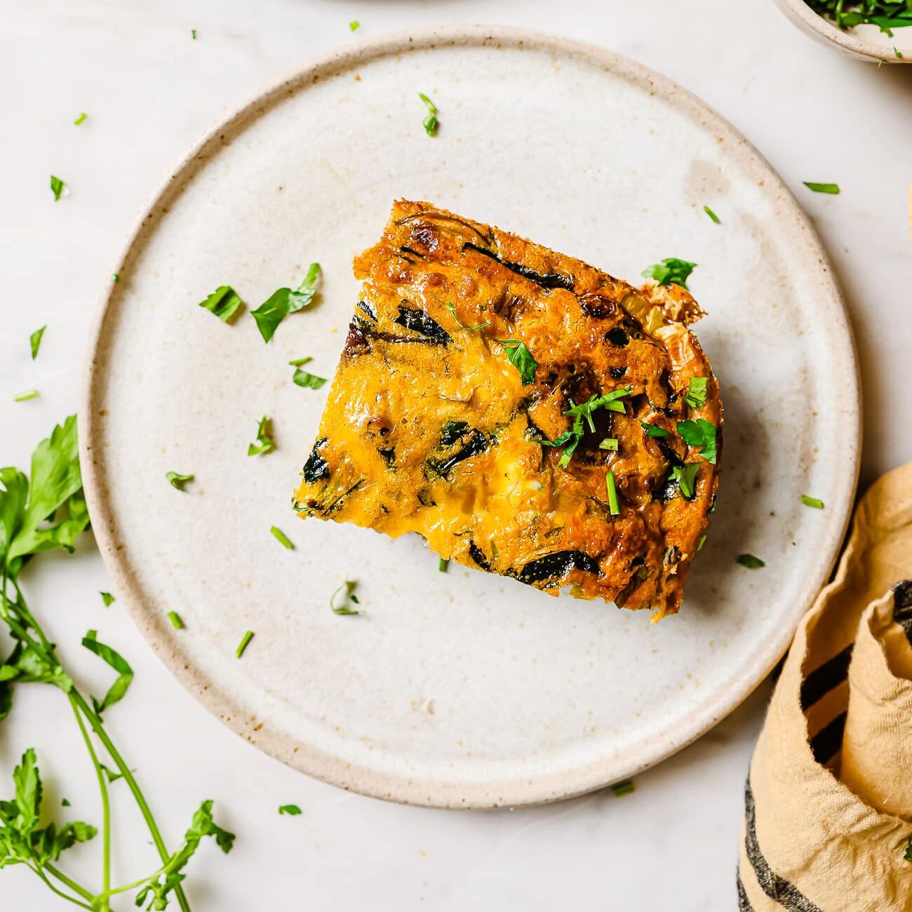 A piece of spinach mushroom frittata on a white plate. 
