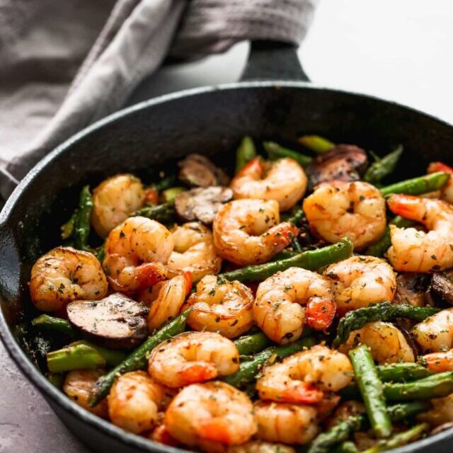 Sauteed shrimp, asparagus and mushrooms in a skillet.