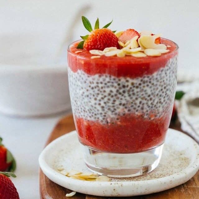 Strawberry chia seed pudding in a glass topped with sliced almonds.