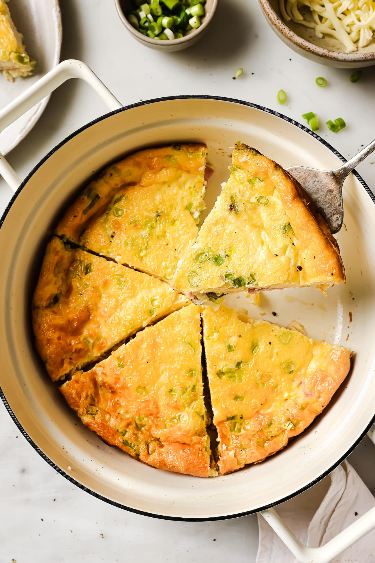 Crustless ham and cheese quiche cut into slices in a pie dish.