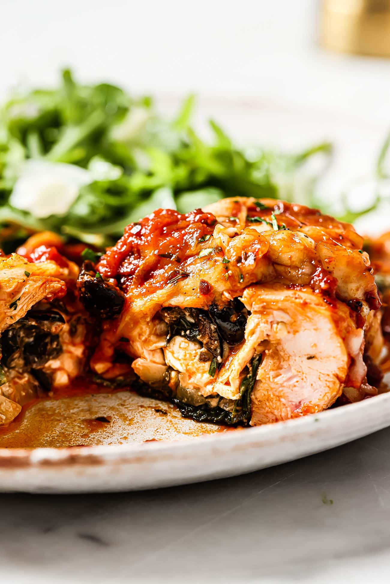 A closeup of spinach and feta stuffed chicken on a white plate.