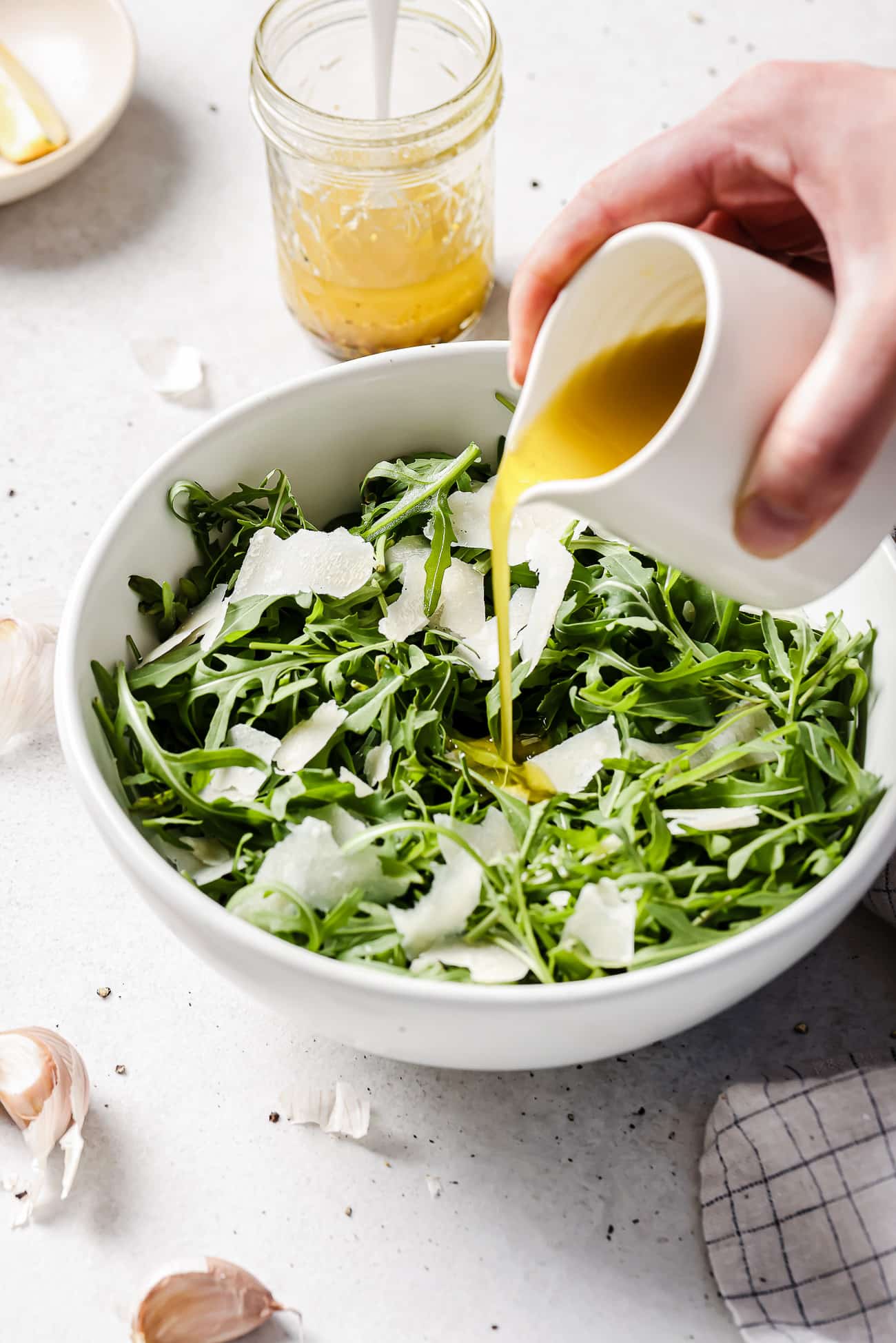 Vinaigrette dressing being poured over an arugula salad.