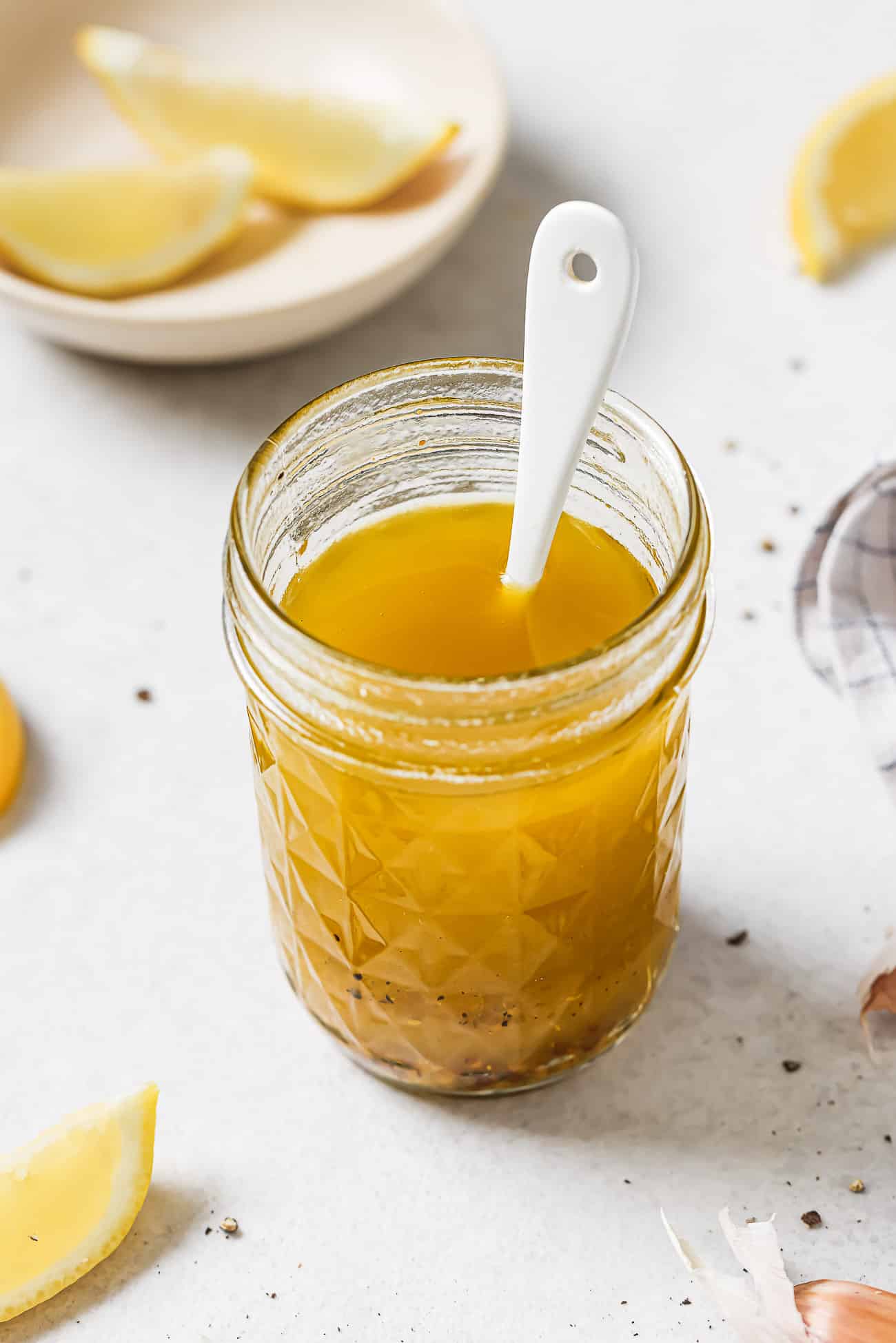 Vinaigrette dressing in a jar with a white spoon in it.