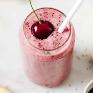 a glass of cherry smoothie on a countertop