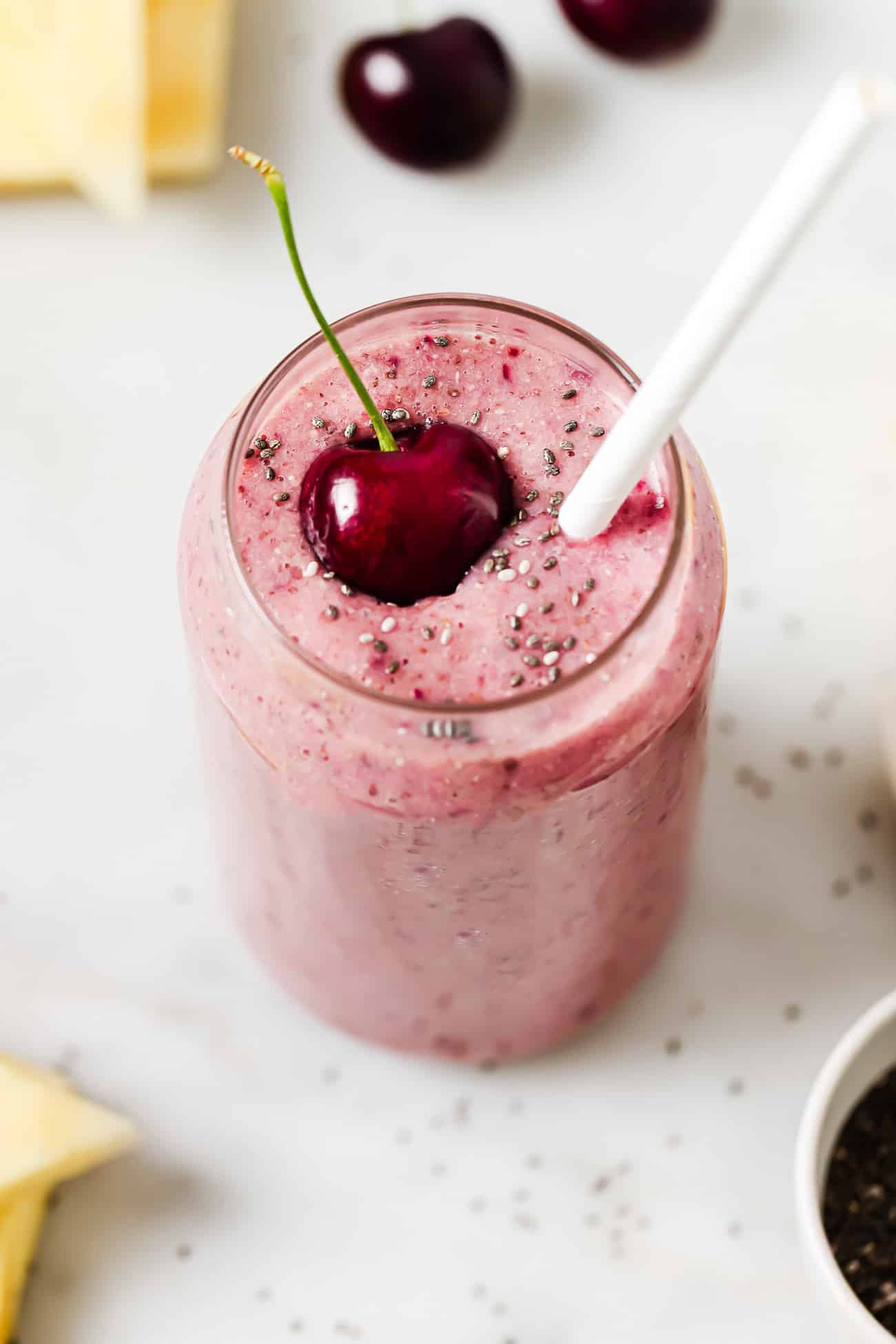 Overhead photo of a cherry smoothie in a glass garnished with a fresh cherry.