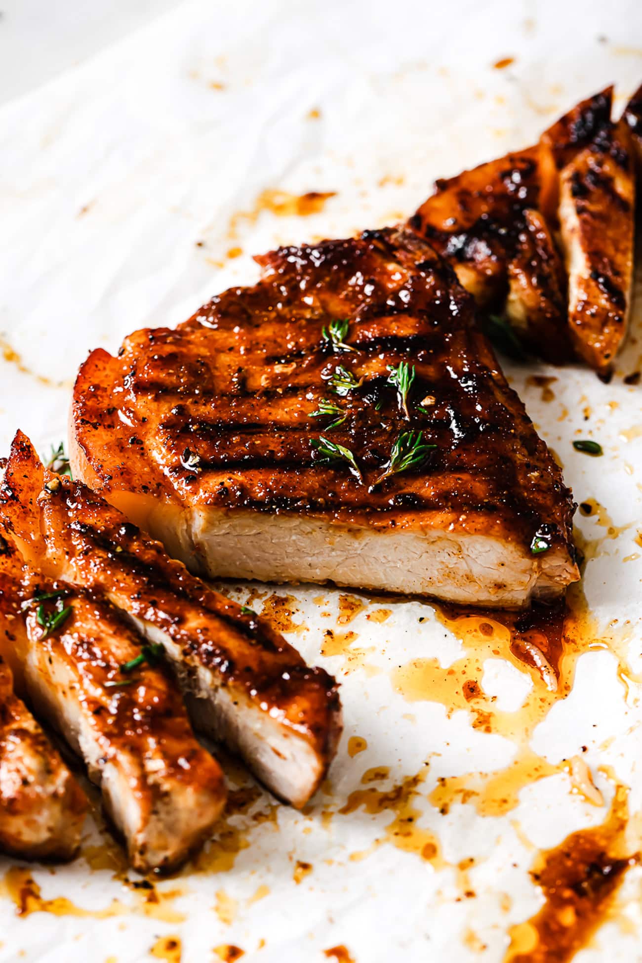 Grilled pork chops sliced and garnished with fresh thyme.