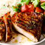 closeup of grilled pork chops on a plate with rice and salad