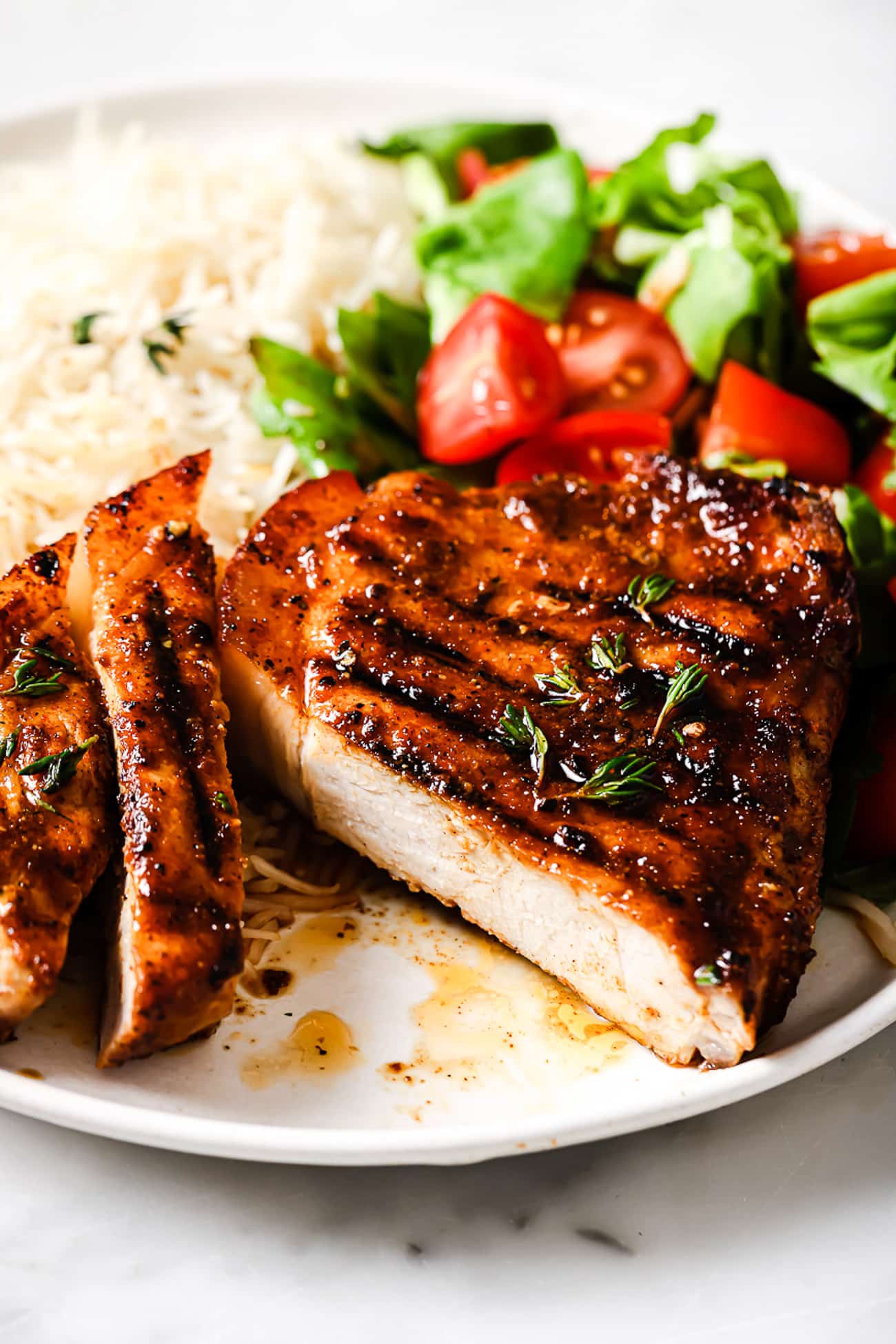 Grilled pork chops on a plate with white rice and a salad.