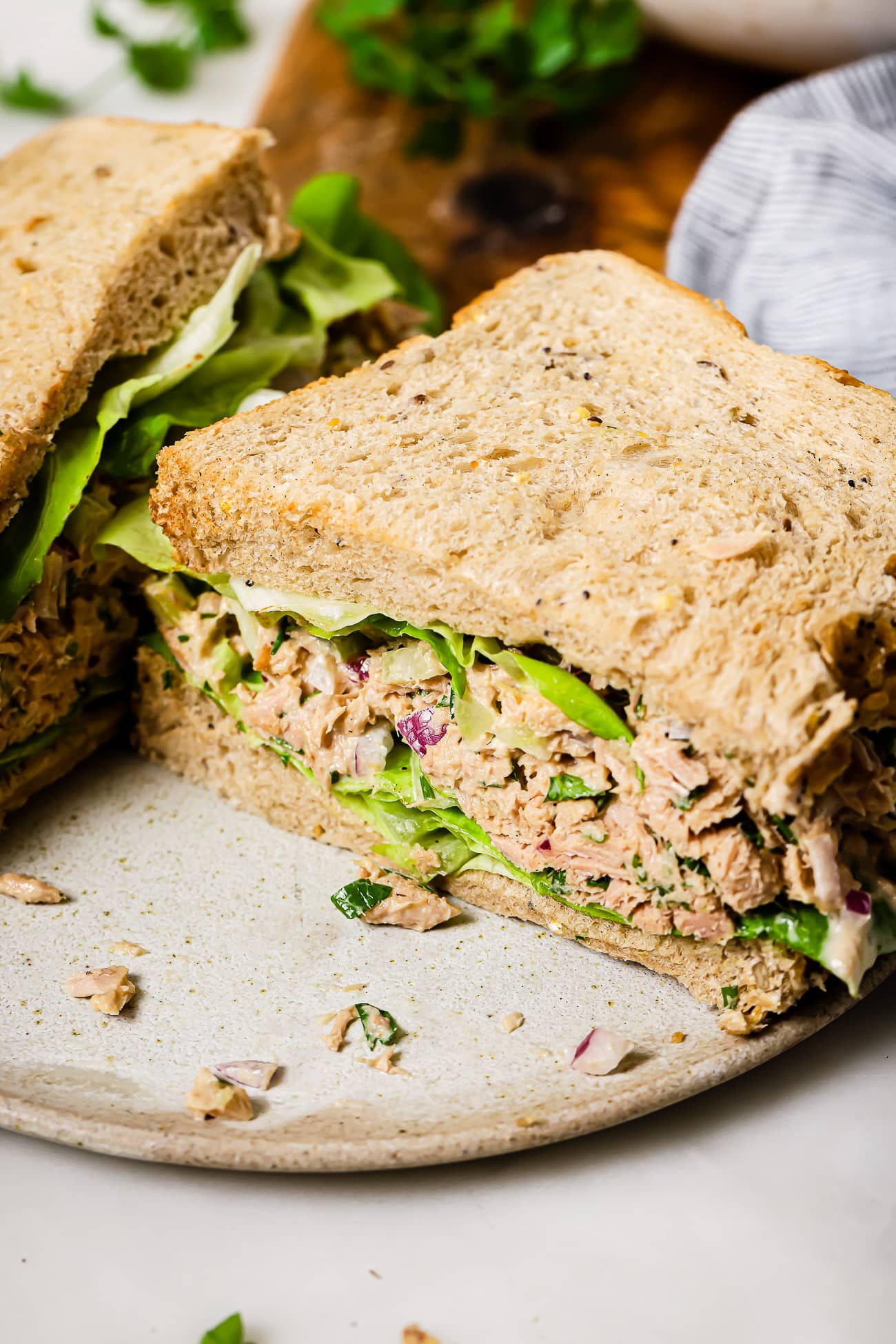Half of a tuna salad sandwich with lettuce on a plate.