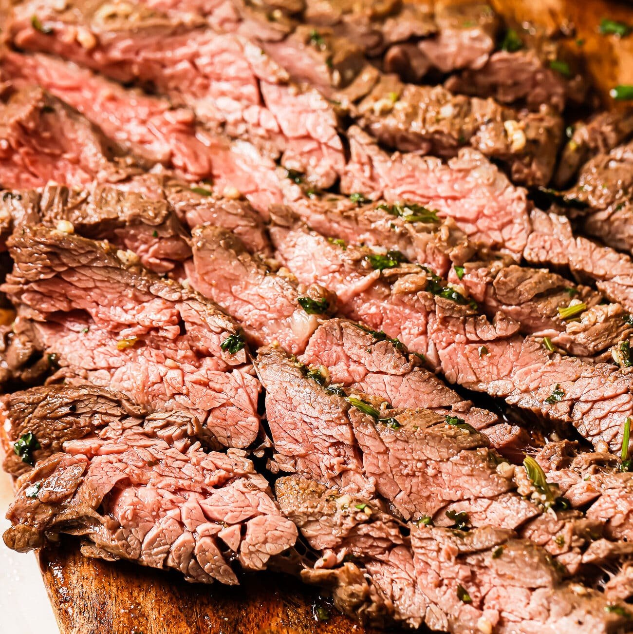 A close-up of thin-sliced carne asada on a cutting board.