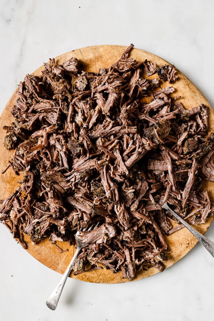 Shredded barbacoa on a wooden cutting board.