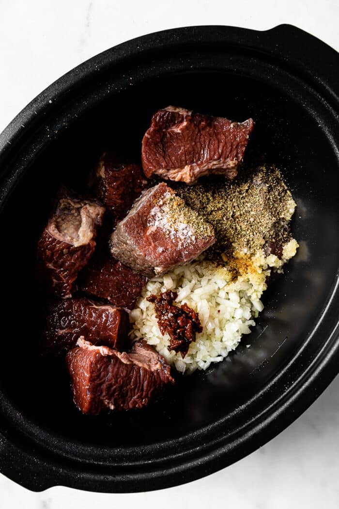 Beef, onions, garlic, and seasonings in a slow cooker. 
