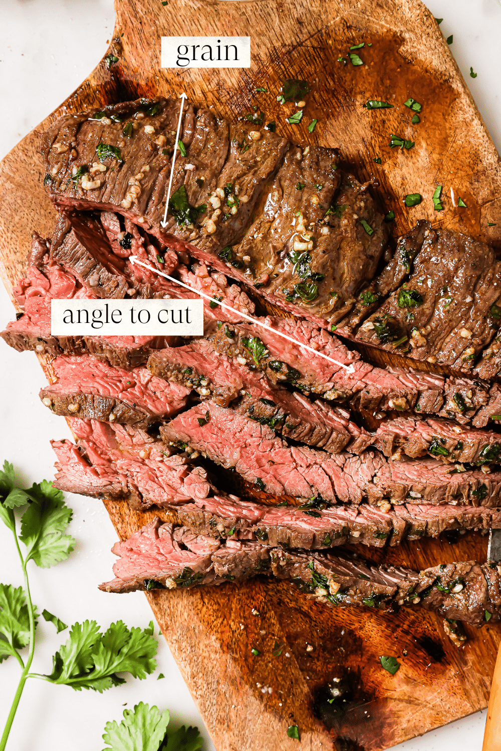 An overhead view of thinly sliced carne asada on a wooden cutting board.