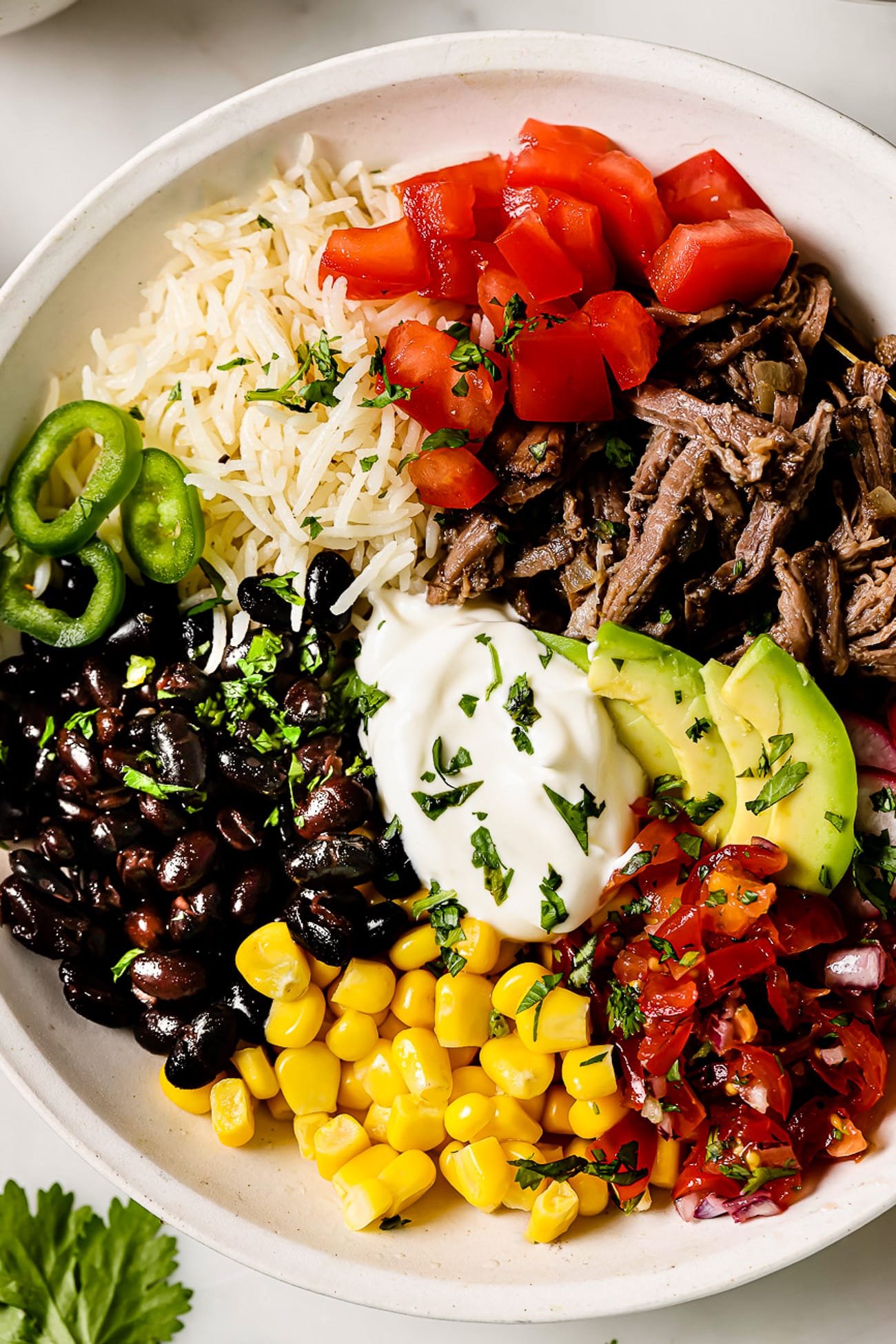 A barbacoa burrito bowl with pico de gallo, corn, black beans, and toppings.