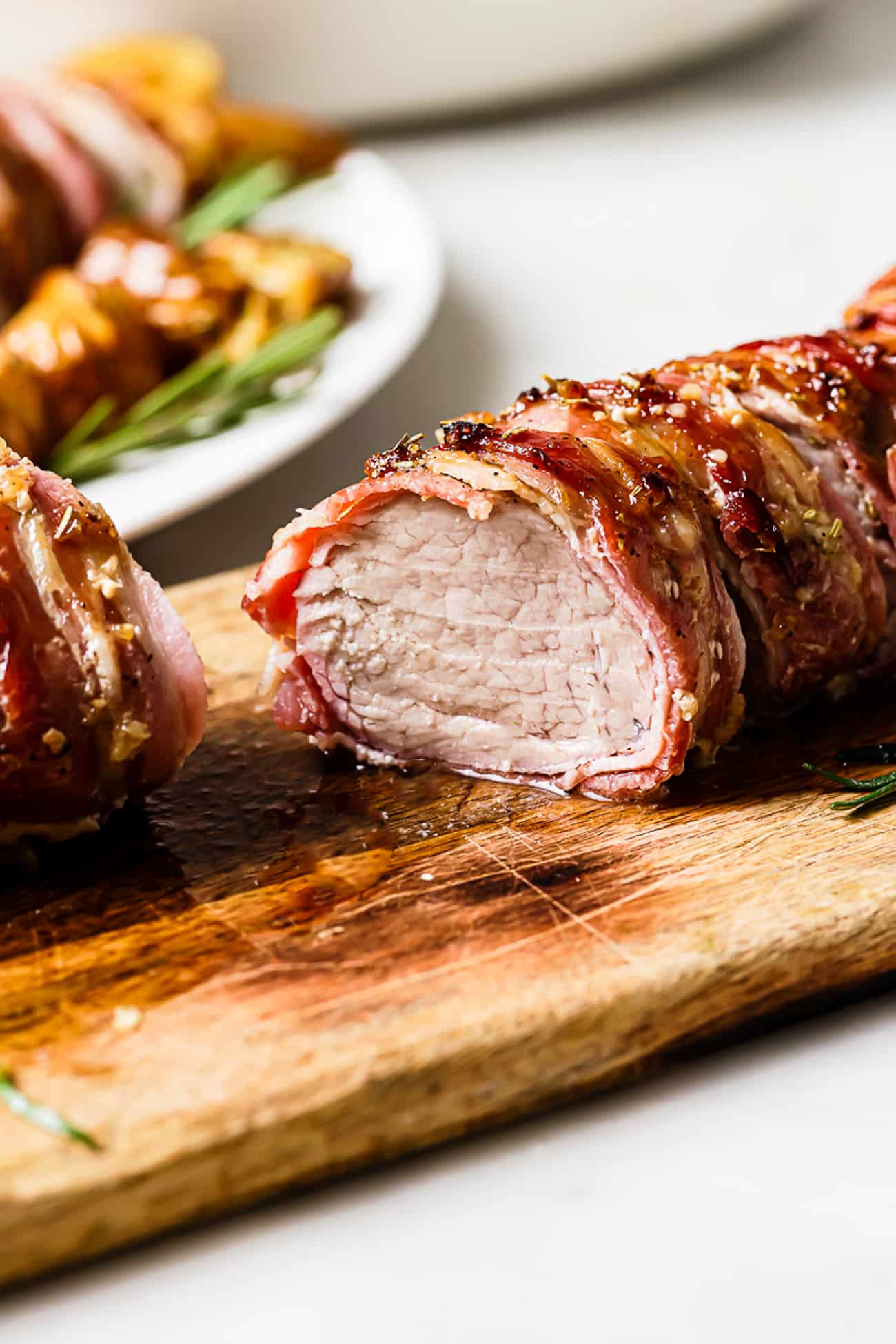 A side view of sliced pork tenderloin wrapped in bacon. 