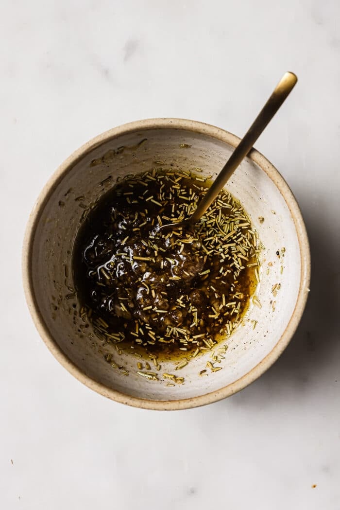 An overhead view of olive oil, seasonings, and brown sugar in a small bowl. 