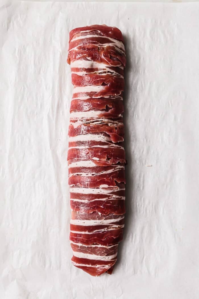 An overhead view of a bacon wrapped pork tenderloin. 