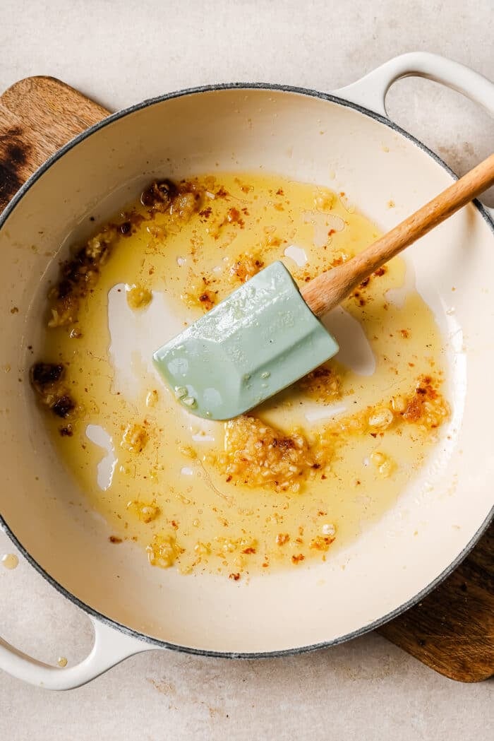 Olive oil and garlic in a large white skillet. 