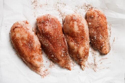 raw chicken breast with seasonings on top.