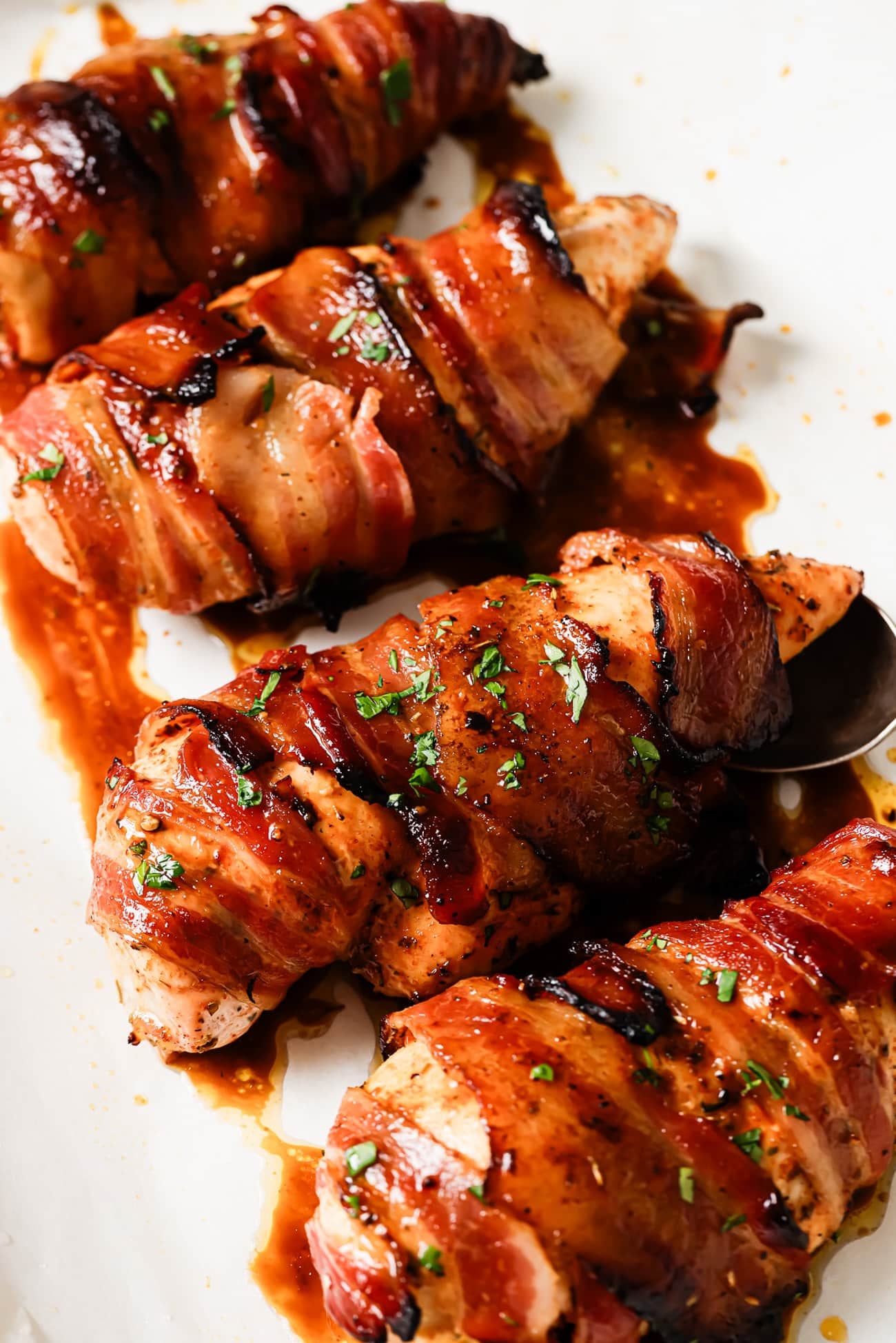 A close-up of bacon-wrapped chicken breasts garnished with parsley.