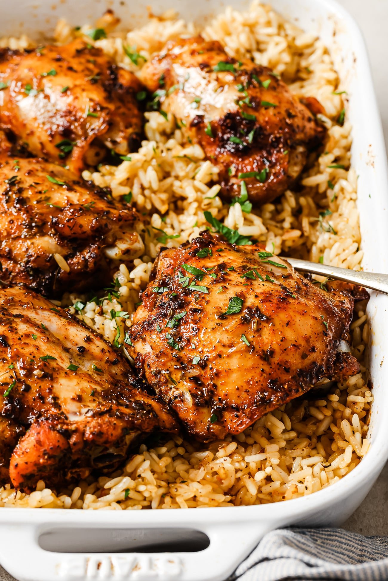 An overhead view of baked chicken and rice in a white casserole dish.