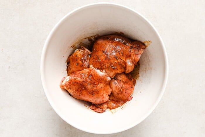raw chicken thighs in a white bowl