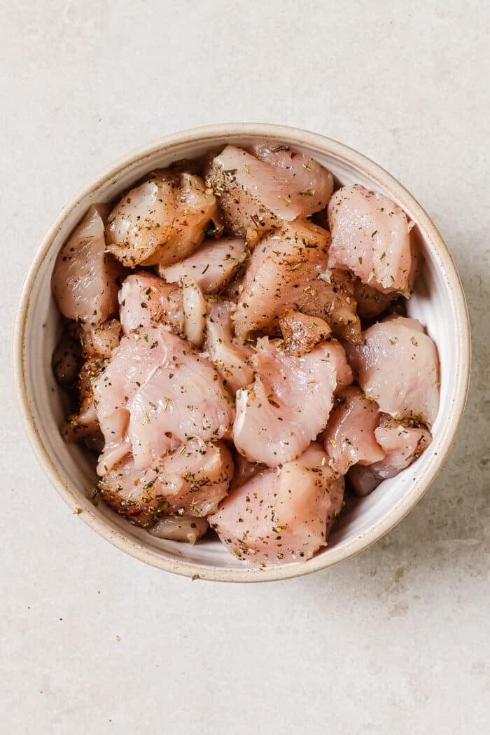 Seasoned raw chicken in a white bowl