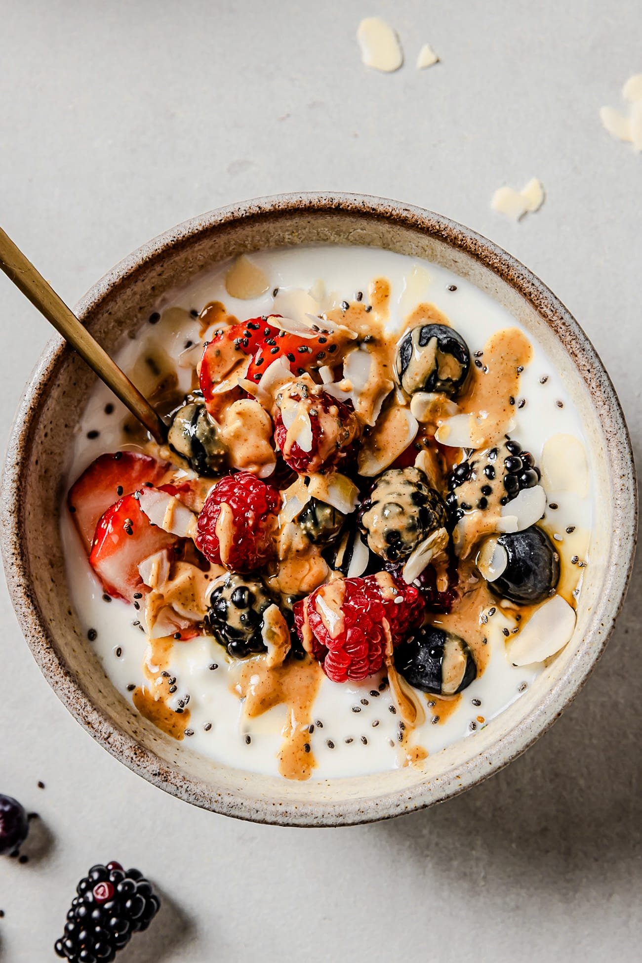 A cottage cheese breakfast bowl topped with mixed berries, chia seeds, maple syrup, and peanut butter.