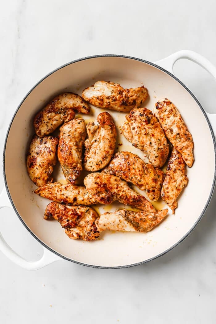 Cooked chicken tenders in a large ceramic cast-iron skillet.