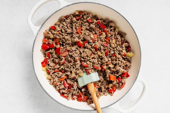 sauteed onions, bell pepper and ground beef in a white skillet
