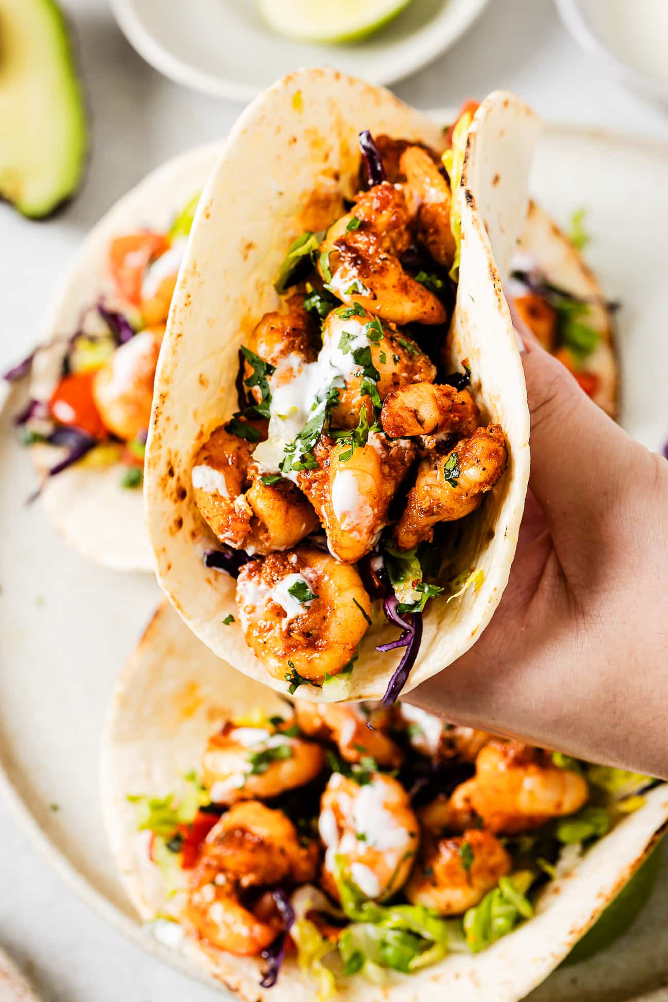 A side-view of a shrimp taco topped with sour cream and cilantro.