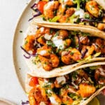 close up of 3 shrimp tacos on a white plate