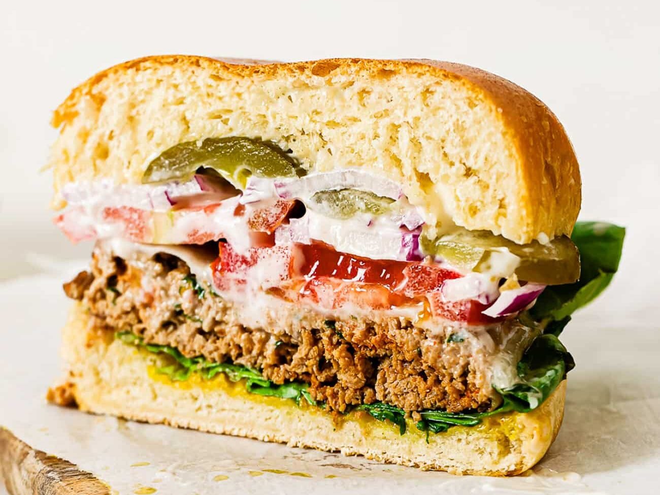 A side view of a ground turkey burger with layers of toppings cut in half.