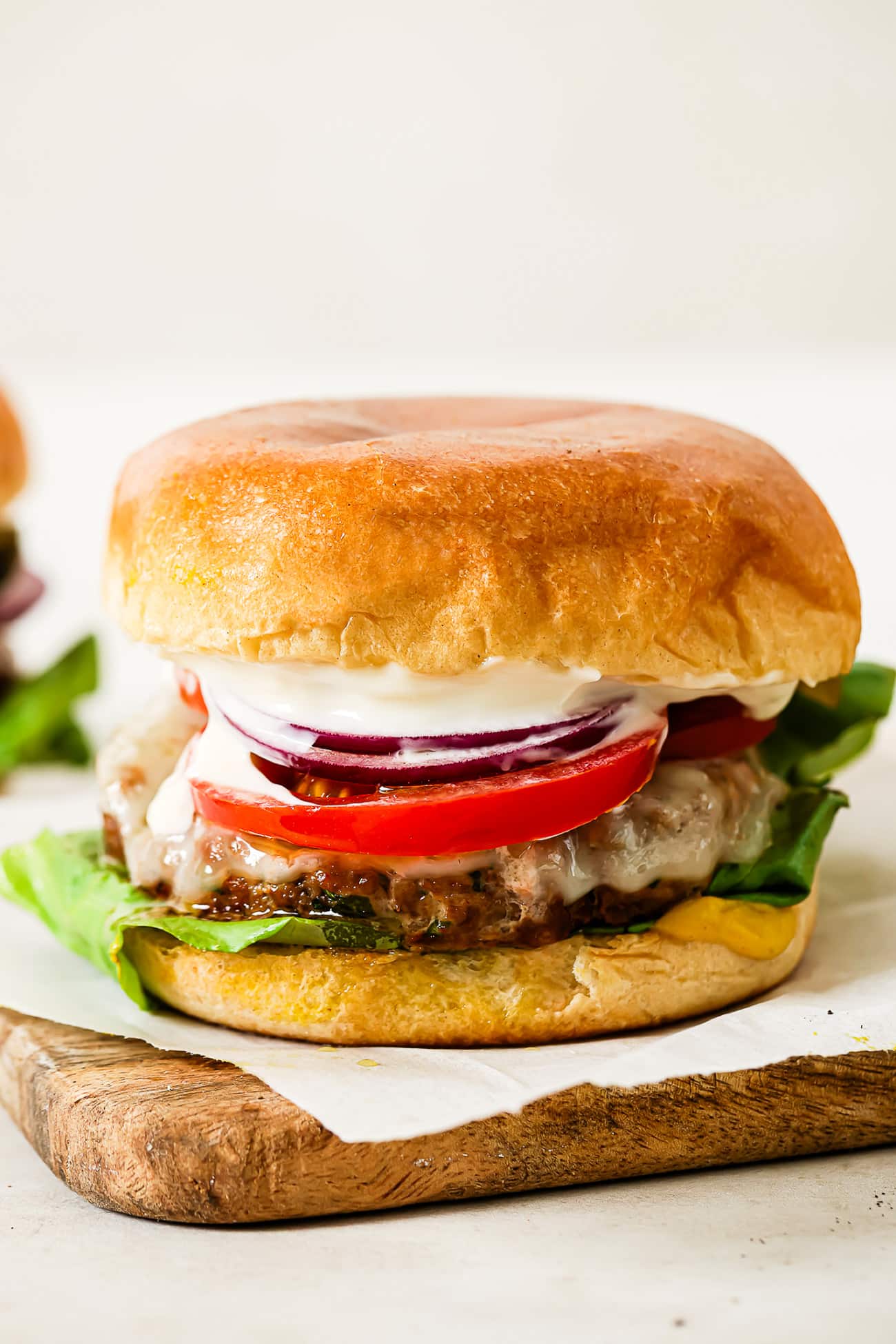 A close-up of a ground turkey burger on a piece of parchment paper over a cutting board.
