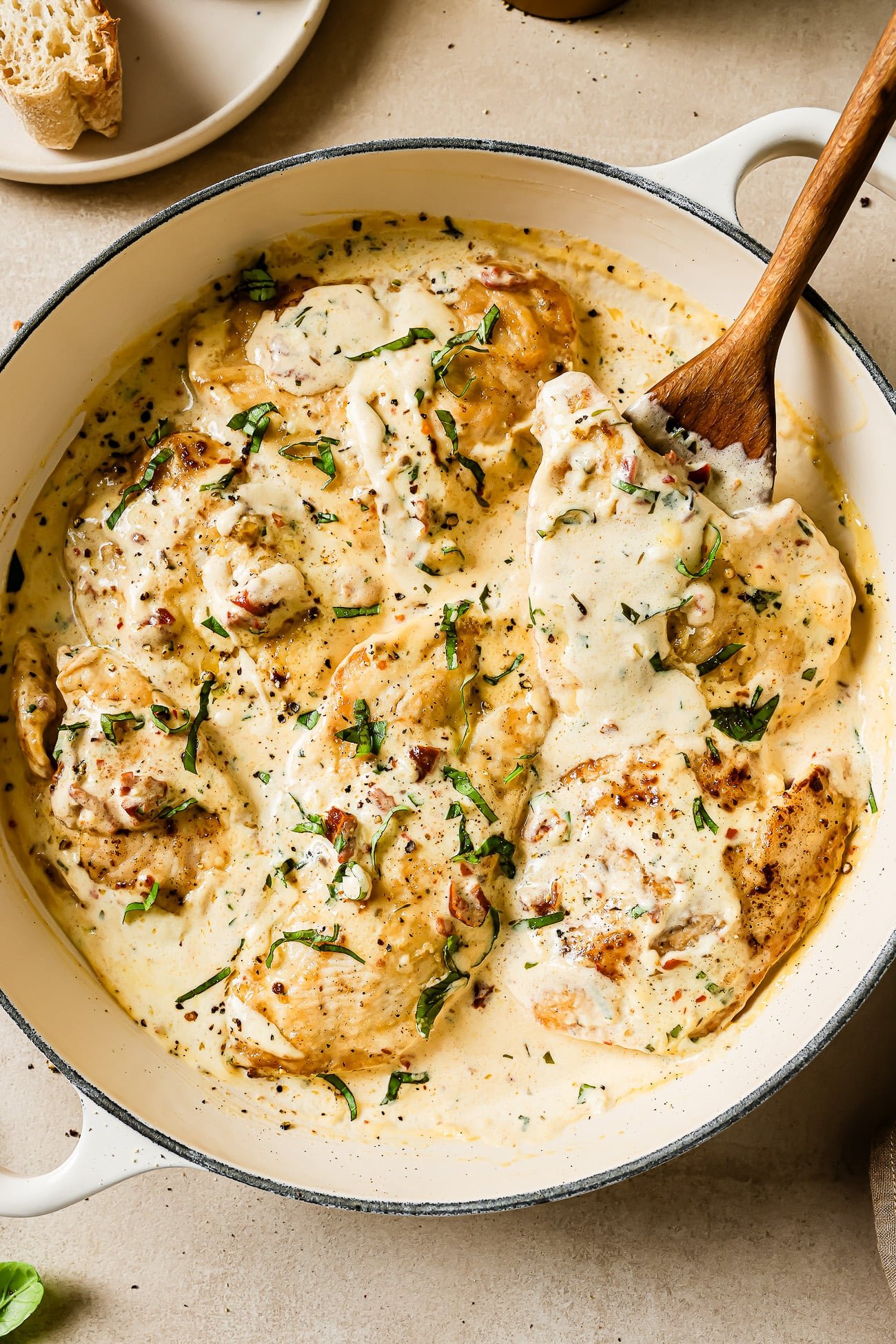 Mary me chicken in a large skillet with a wooden serving spoon.