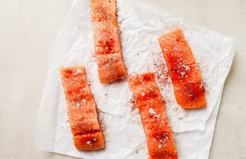 Overhead view of raw, seasoned salmon fillets resting on a paper towel on the kitchen countertop.