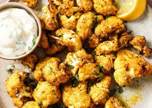 Overhead view of crispy air-fried cauliflower on a white plate.
