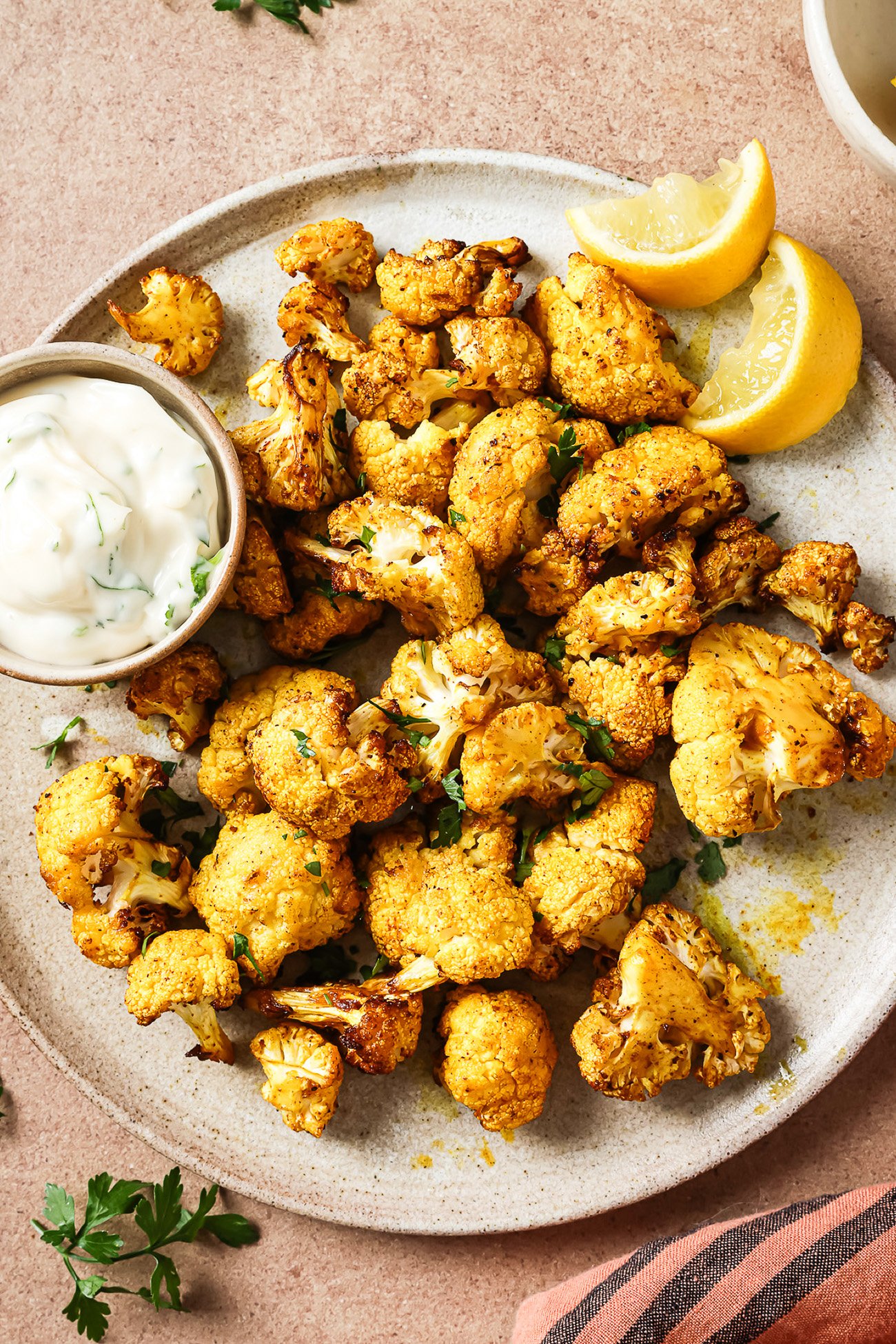 Overhead view of crispy air-fried cauliflower on a white plate.