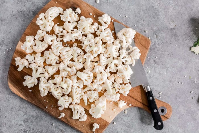Cauliflower florets on a wooden board.
