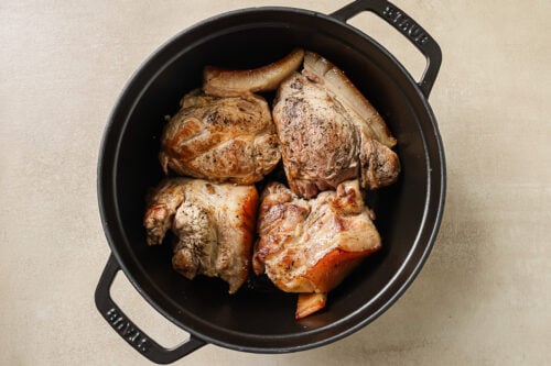 pork shoulder pieces in a black Dutch oven pot.