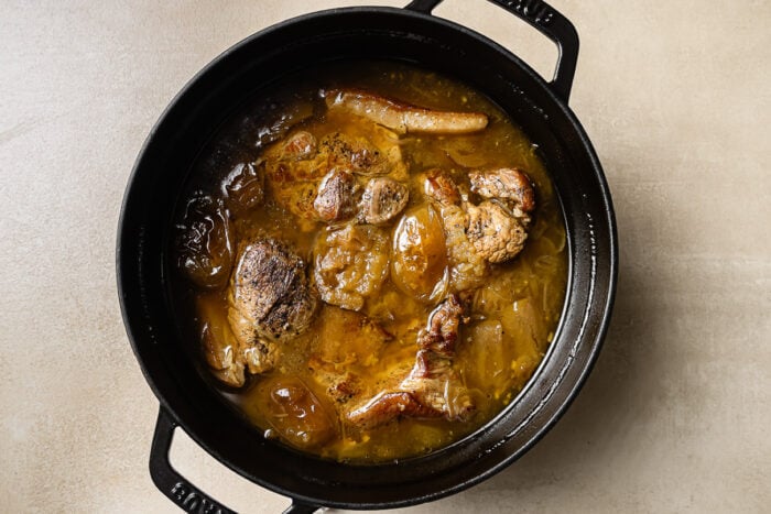 overhead view of apple cider braised pork shoulder in a black Dutch oven pot. 
