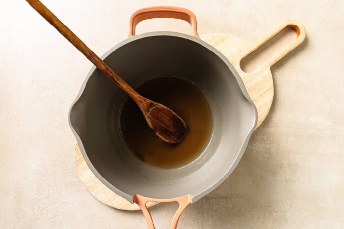 Warm apple cider simmering inside a saucepan.