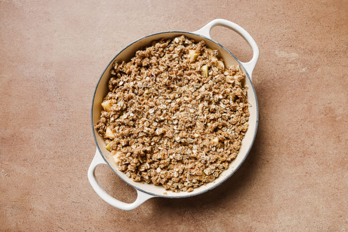 Apple crisp in a white skillet ready to be baked in the oven for a warm and cozy dessert.