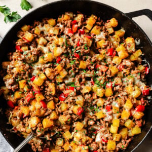 Overhead view of ground beef and potatoes cooked in a cast-iron skillet.