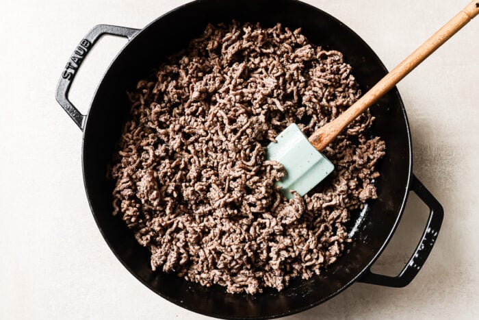 Overhead view of cooked ground beef in a cast-iron skillet, ready to be mixed with vegetables or potatoes.