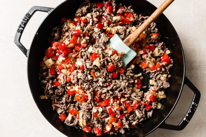 Overhead view of cooked ground beef and vegetables in a cast-iron skillet.